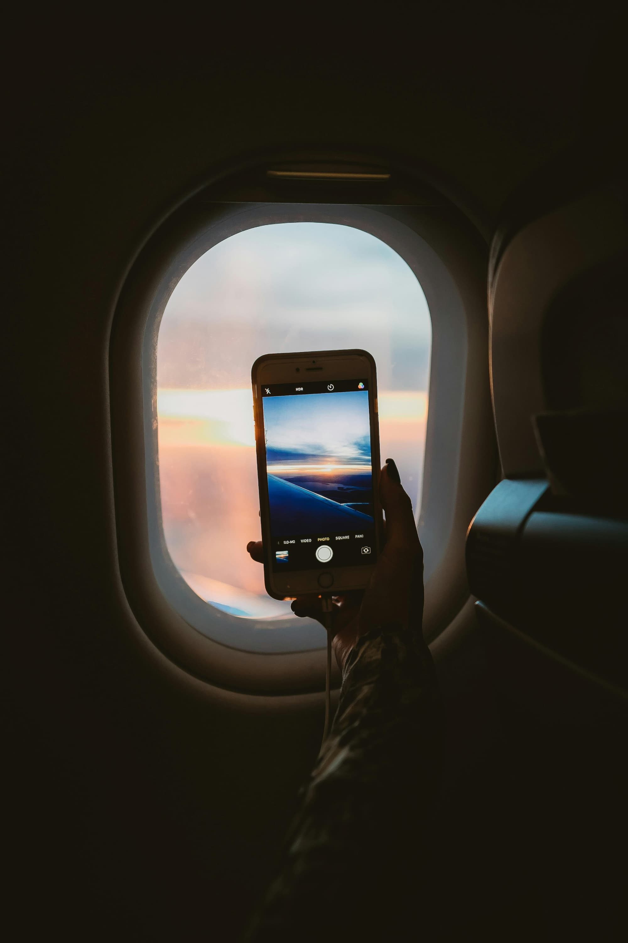 person holding smartphone inside airplane taking a photo