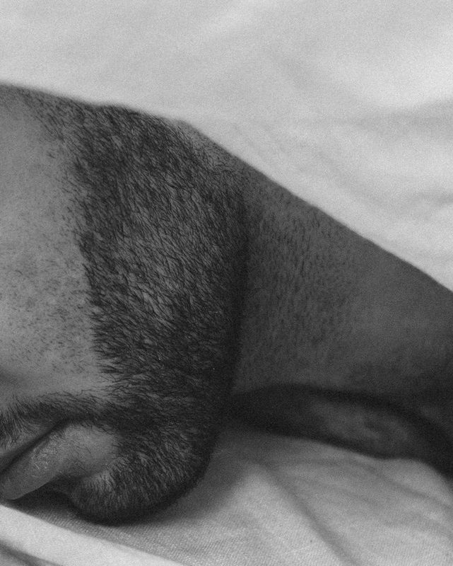 Man sleeping with beard and white blanket over head