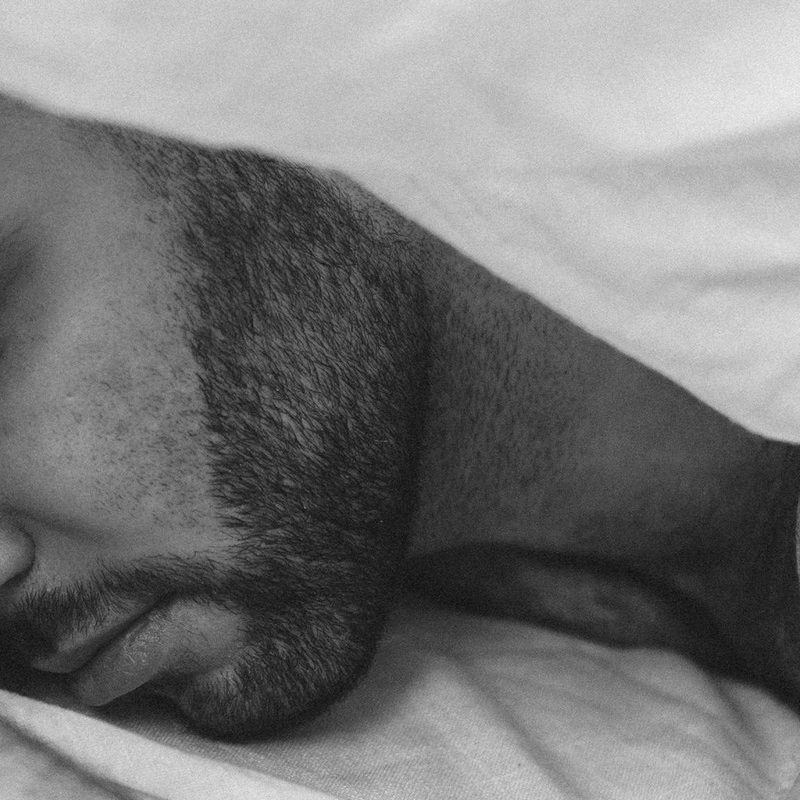 Man sleeping with beard and white blanket over head