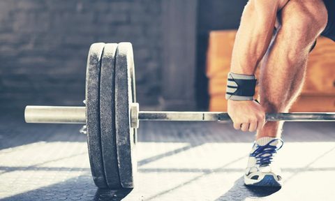 muscular man deadlifting barbell in gym