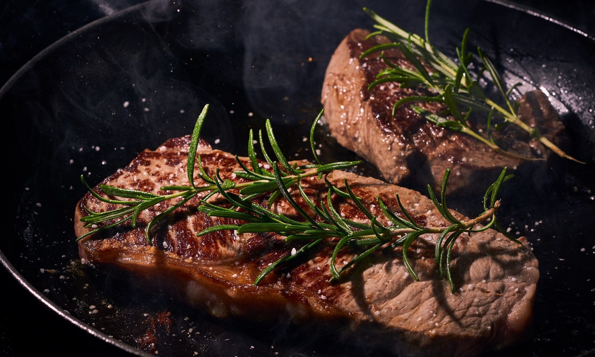 Steak in pan with rosemary