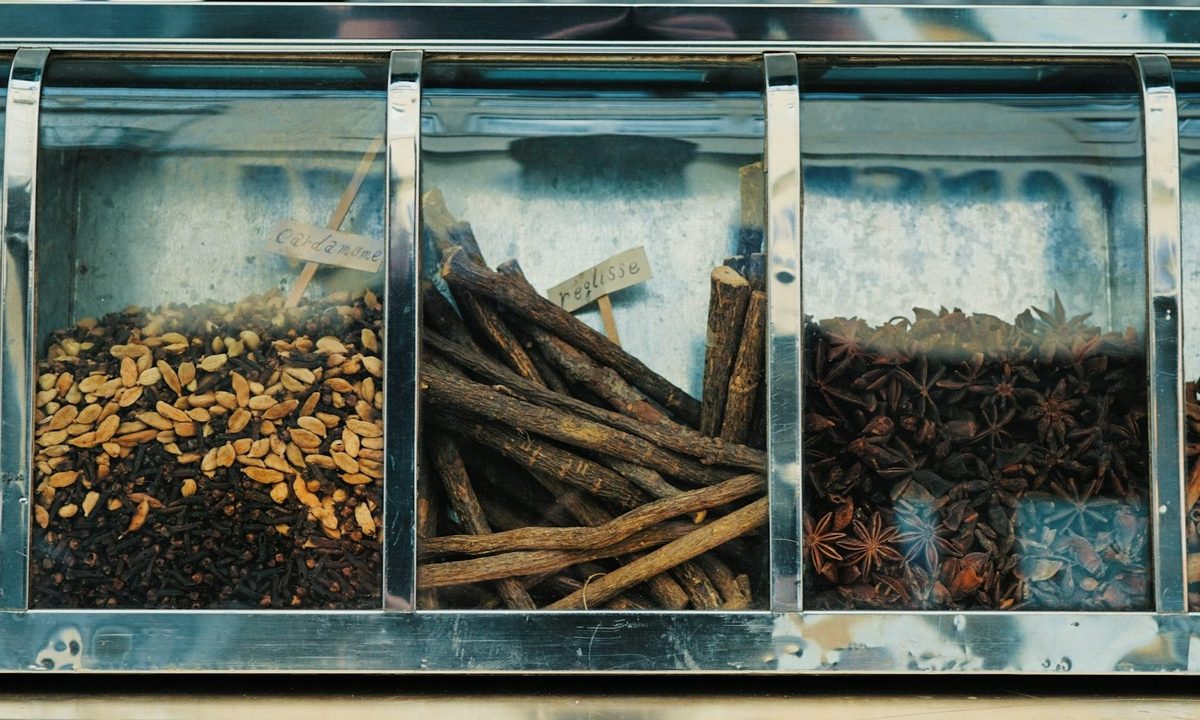 Various flavor items in a cabinet like cinnamon sticks and vanilla.