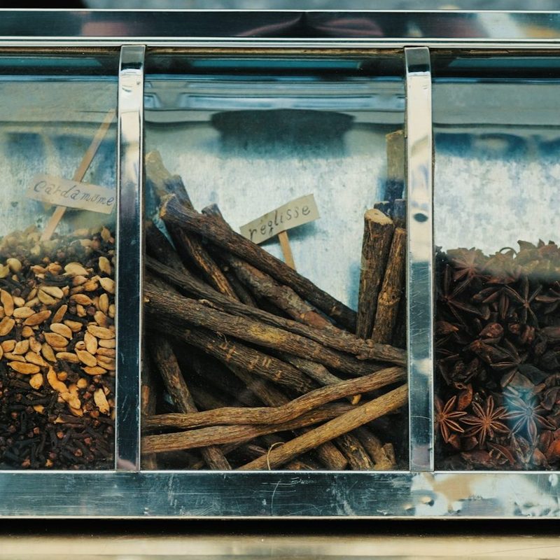 Various flavor items in a cabinet like cinnamon sticks and vanilla.