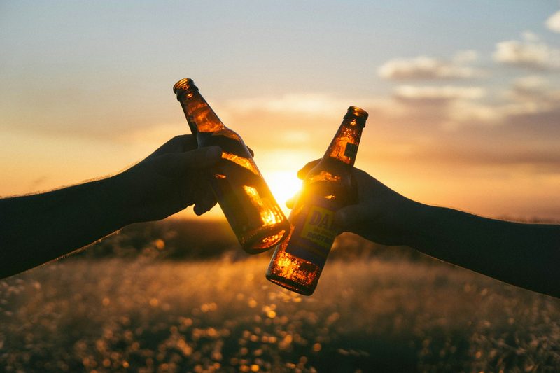 Cheers beer bottles with sun in the background