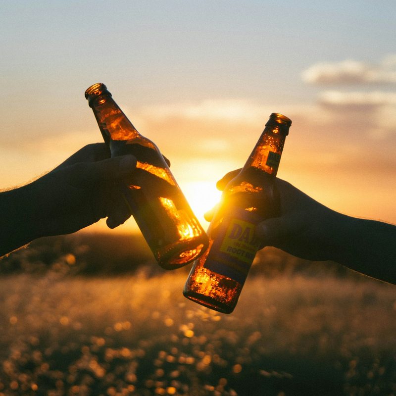 Cheers beer bottles with sun in the background
