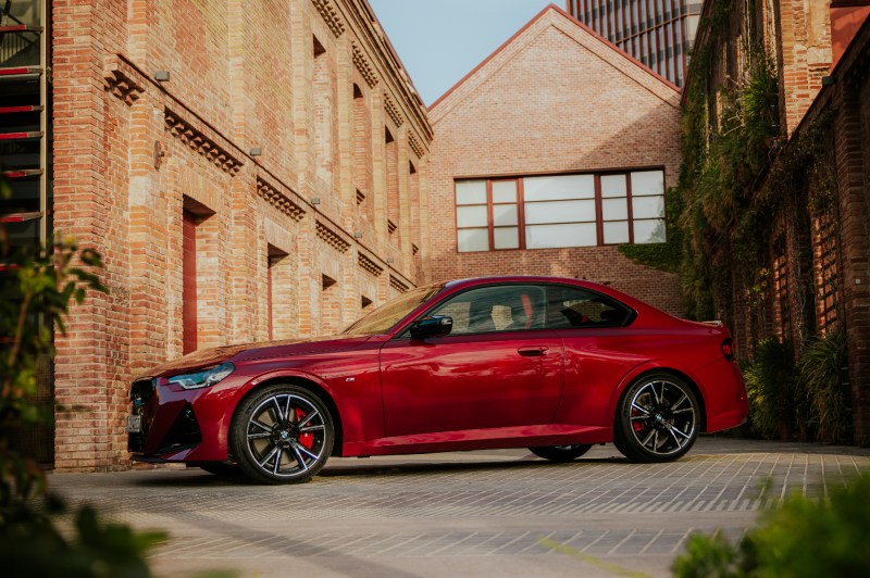 2025 BMW 2 Series Coupe left side view parked on a brick lot between three brick buildingx.