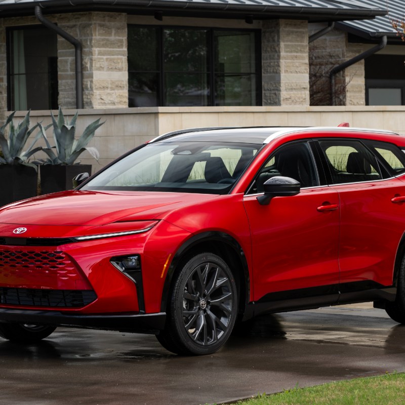 2025 Toyota Crown Signia Limited in Finish Line Red in the rain parked on a driveway in front of a house.