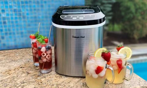 The Magic Chef 27-lbs Countertop Ice Maker next to iced drinks.