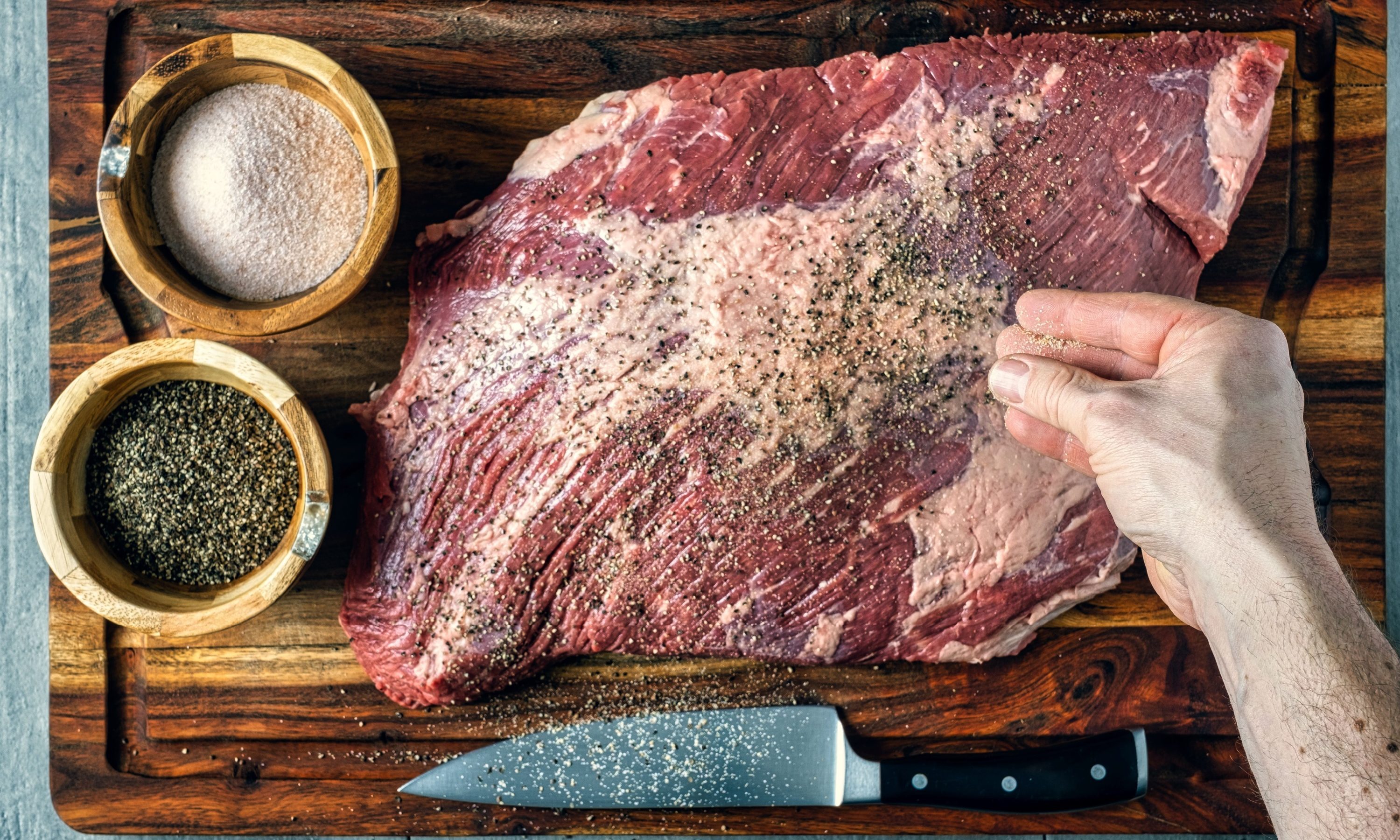 Seasoning a beef brisket with salt and pepper before barbequing on a smoker
