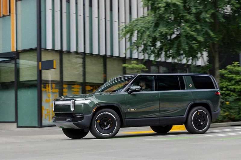 Second-generation Rivian R1S left front three-quarter view turning right on a city street.