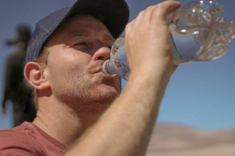 A man taking a drink out of a clear water bottle