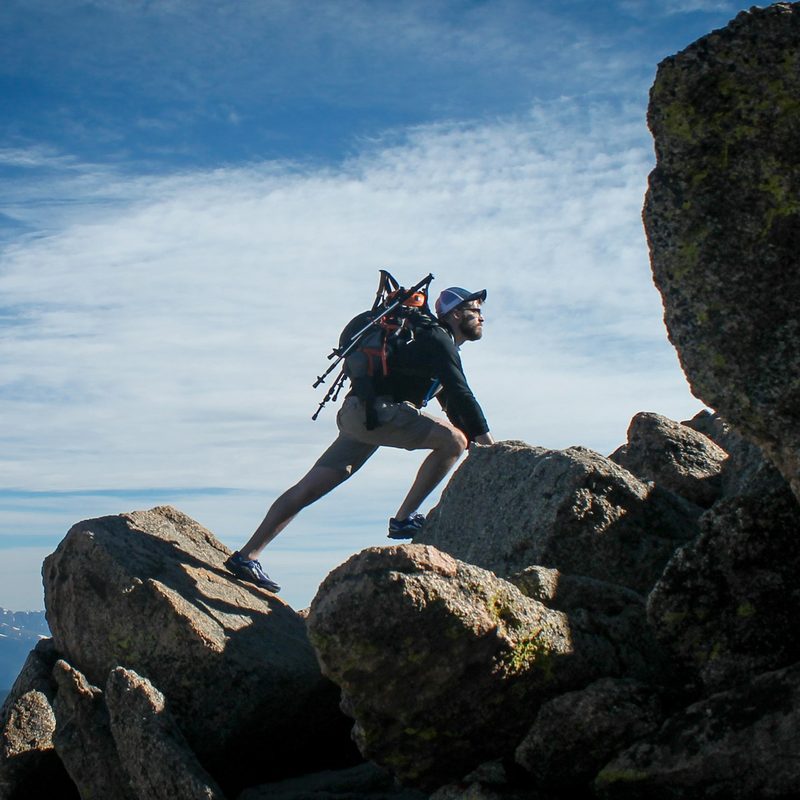 A man straddling two boulders on a hike