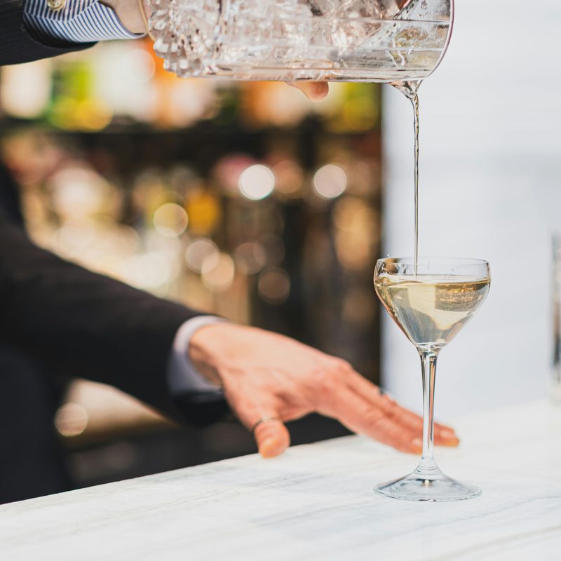 Bartender pouring drink into cocktail glass