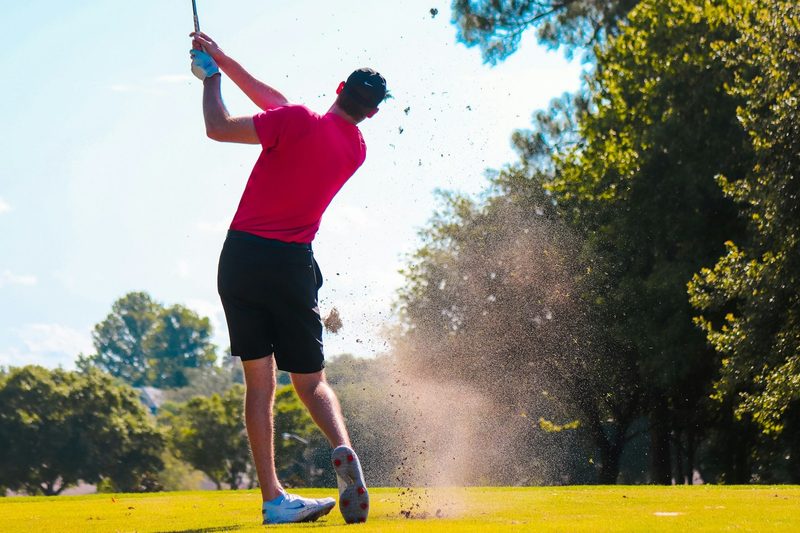A person taking a swing on the golf course.