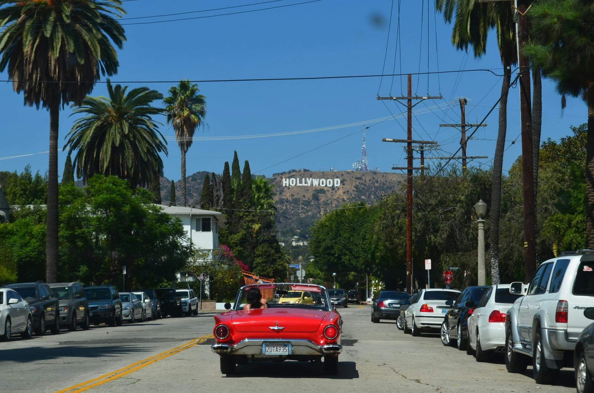 red car on road with hollywood sign in background