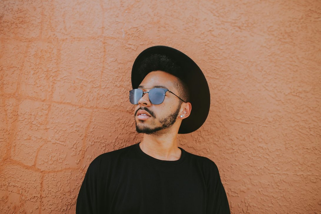 man leaning on wall wearing semi-rimless glasses