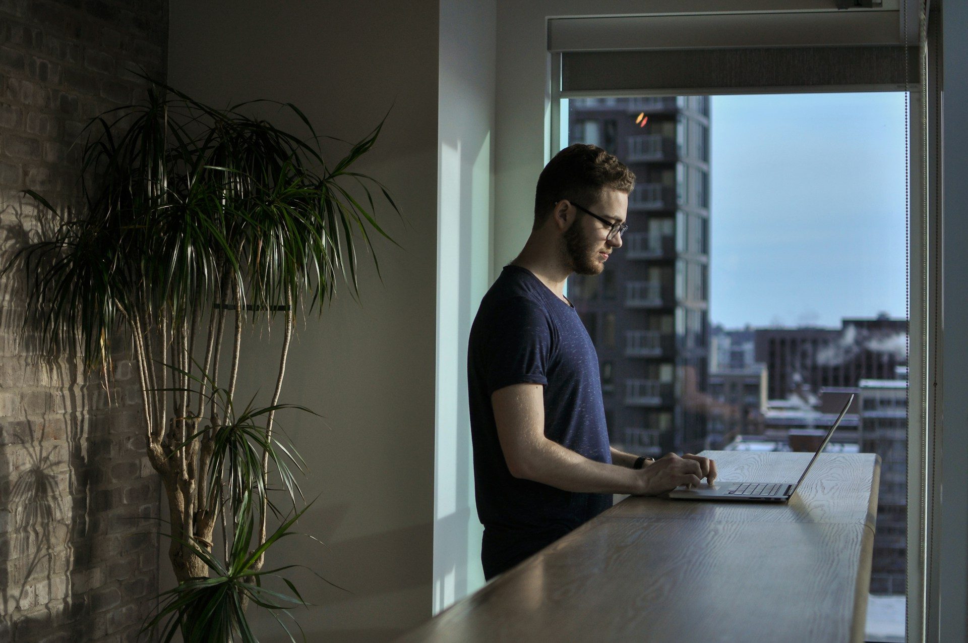 a man standing at a table while working on a laptop