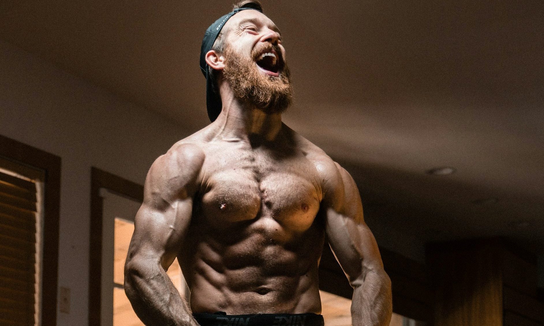 Shirtless muscular man with abs flexing smiling and laughing in a power stance