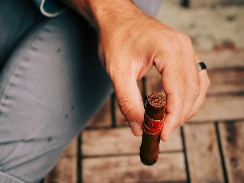 Man holding lit cigar relaxing.