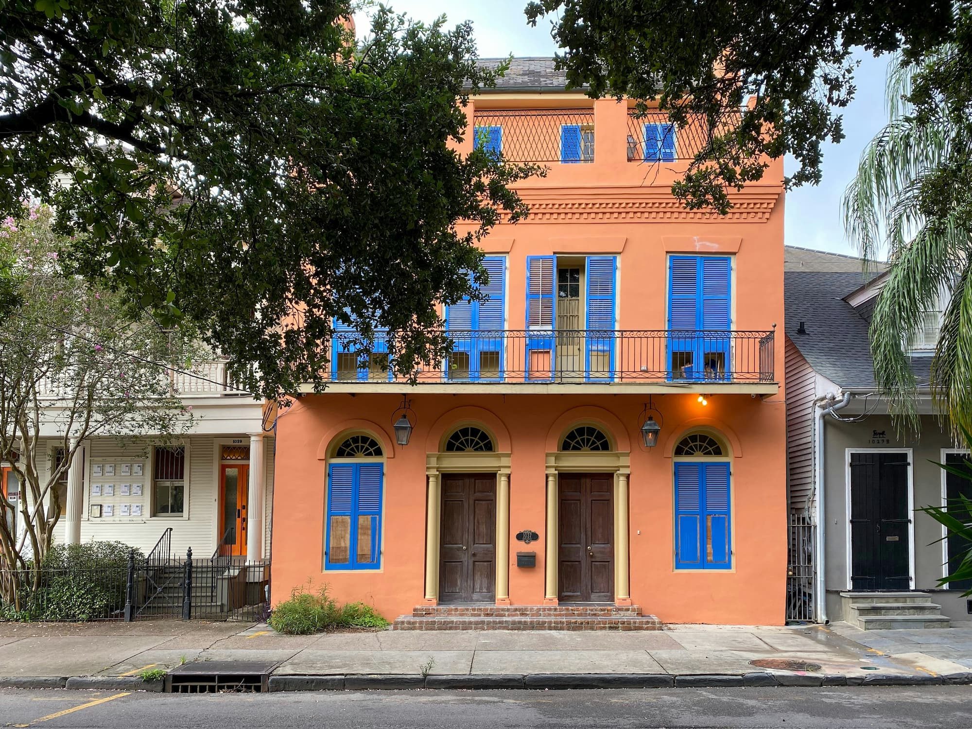 an orange house with blue shutters and a balcony