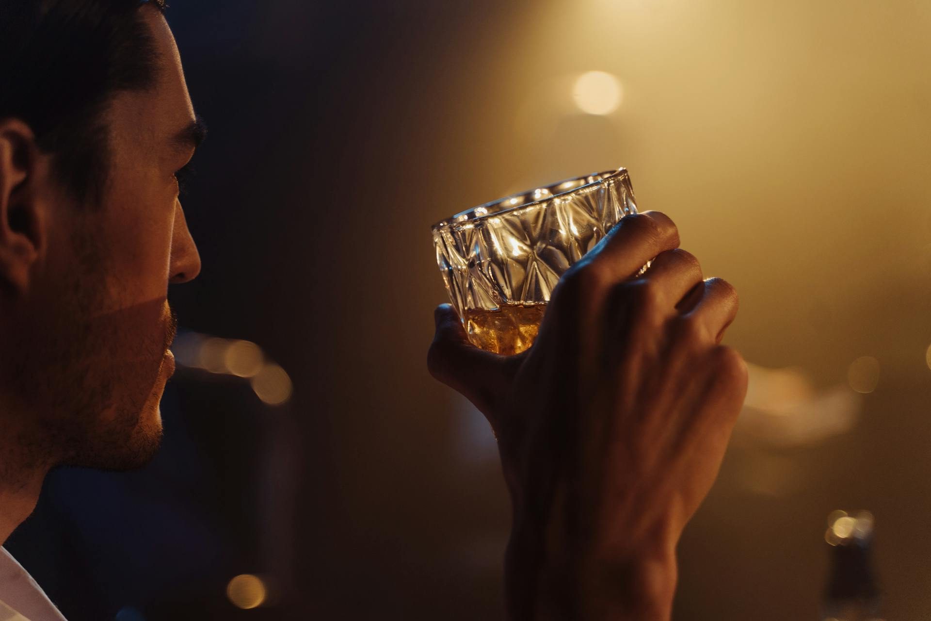 Man in dark bar holding a cocktail glass