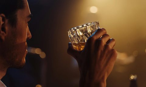 Man in dark bar holding a cocktail glass