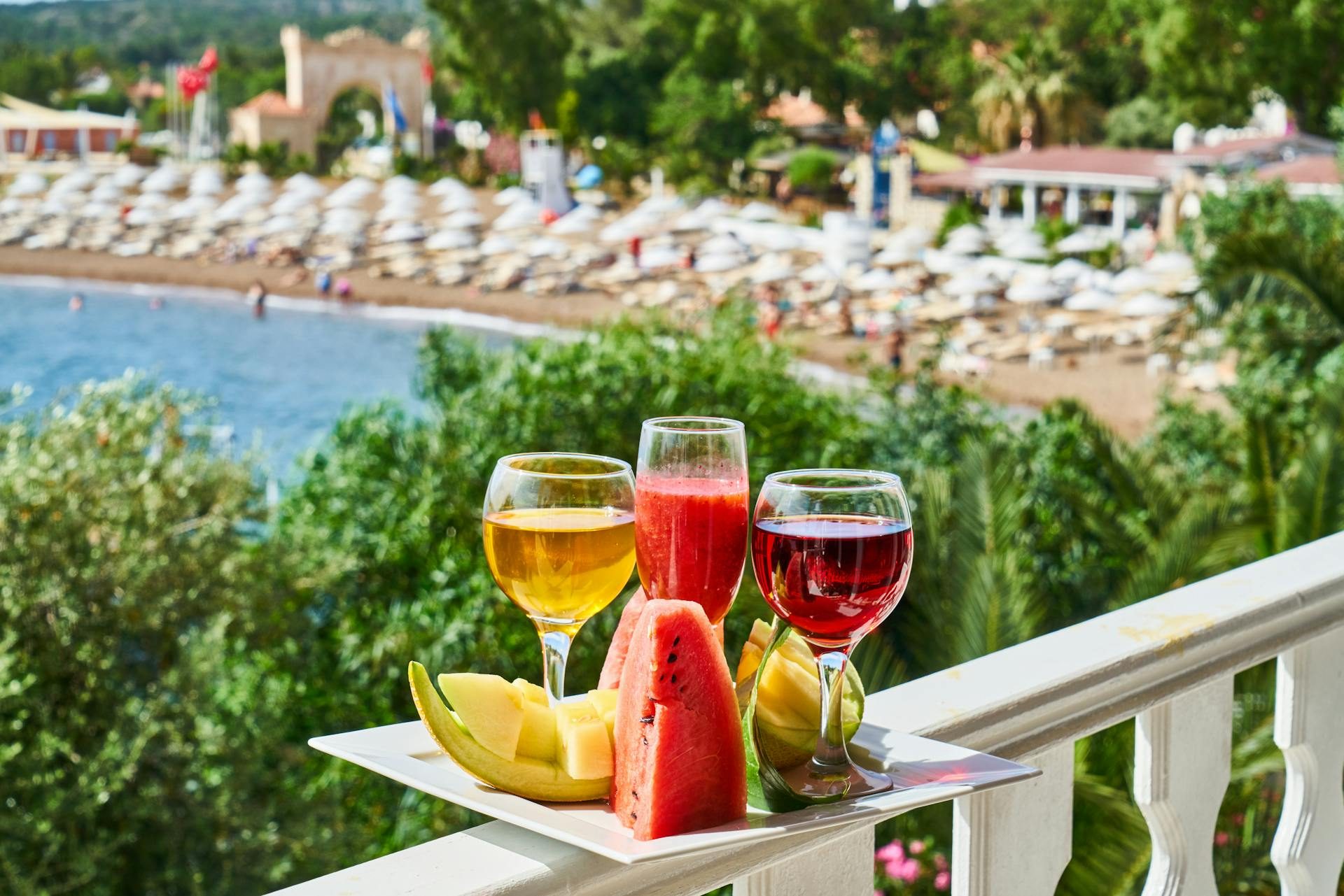 Three cocktails in different wine glasses with pieces of fruit on a plate