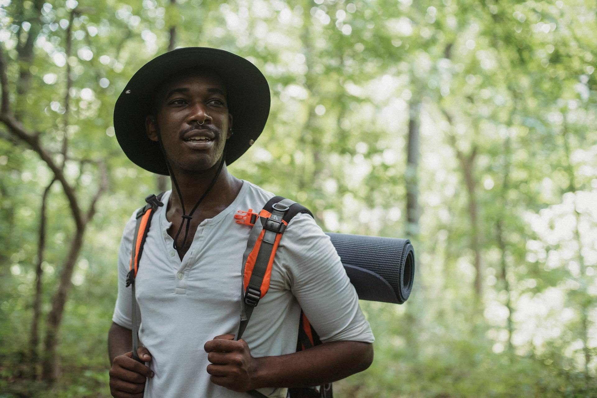 A man with a backpack and sleeping mat walking through the woods