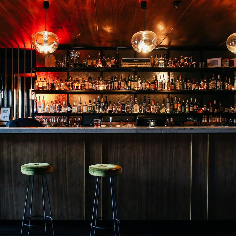 Dark bar with three empty barstools
