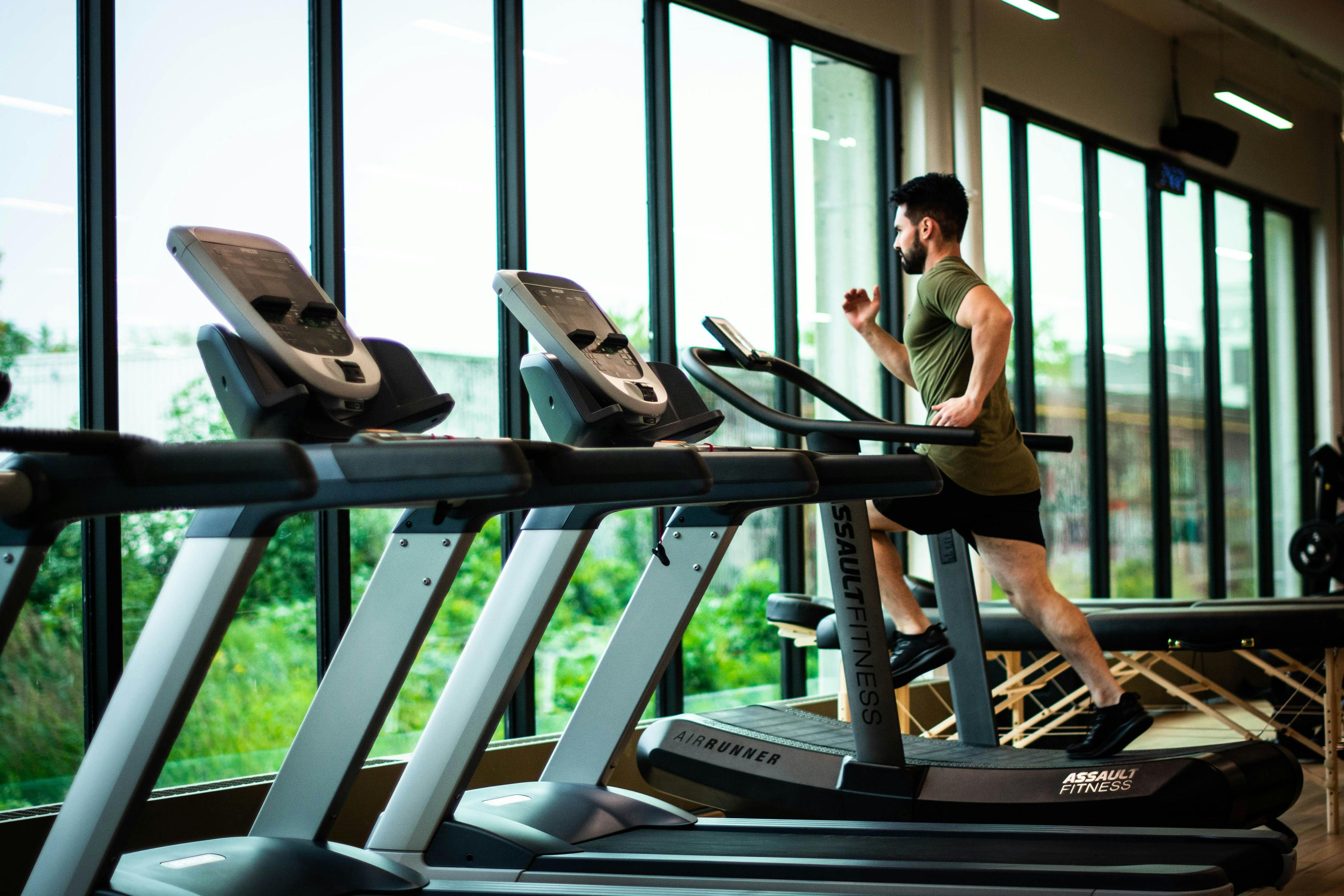 Man on a treadmill in front of windows