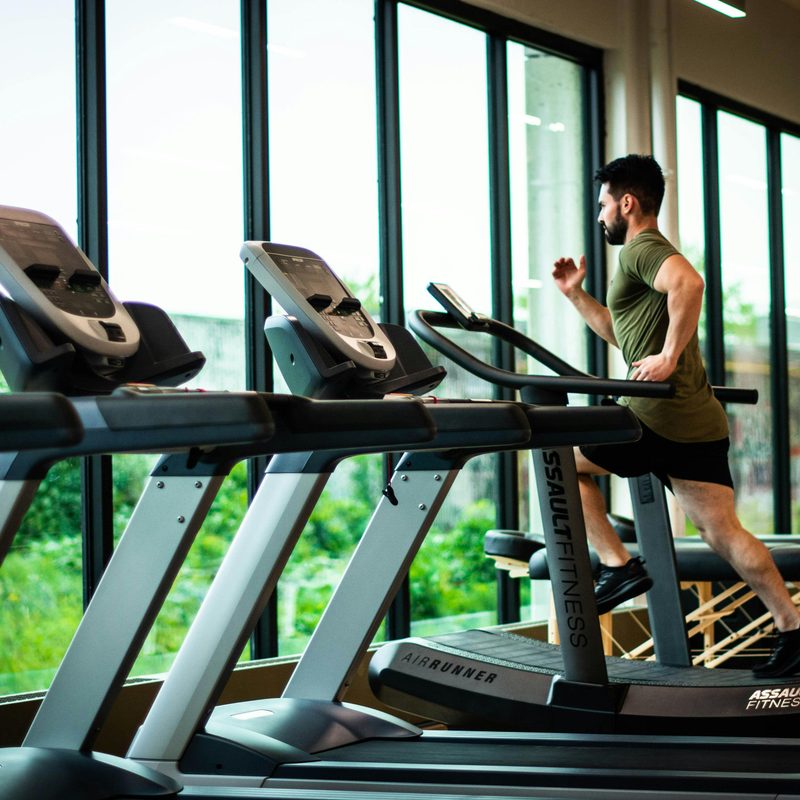 Man on a treadmill in front of windows