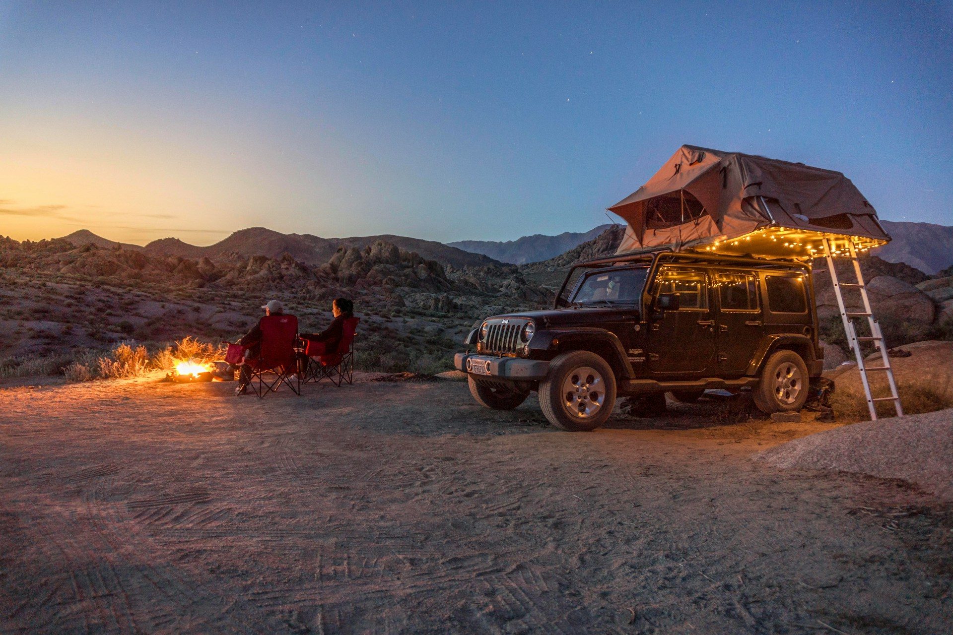 a car with a tent ontop of it in a desert setting at twilight