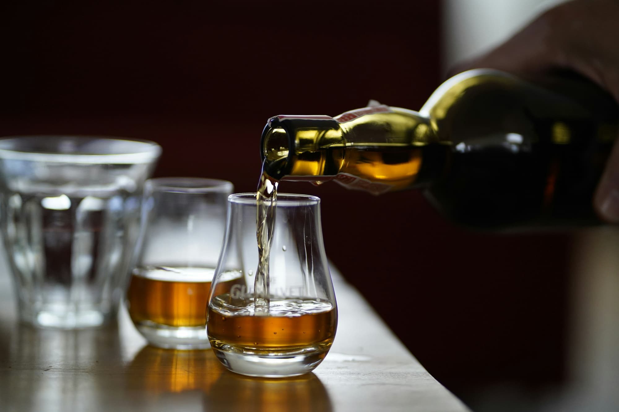 person pouring whisky into two glasses