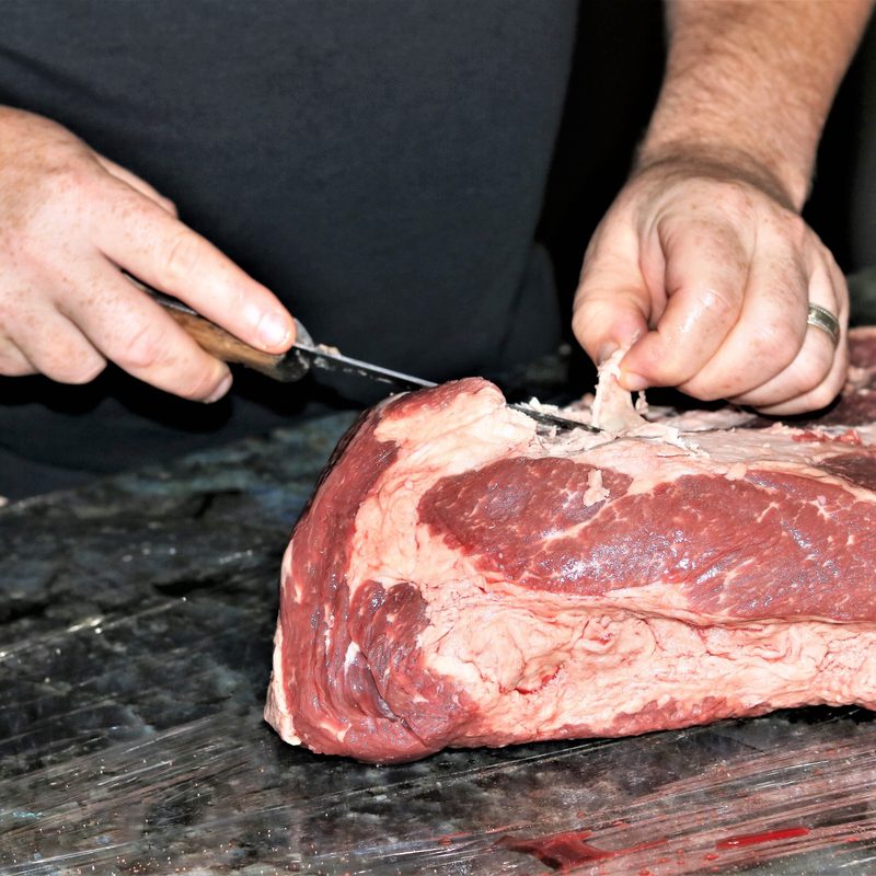 Pieces of fat being carefully trimmed from a fresh beef brisket.