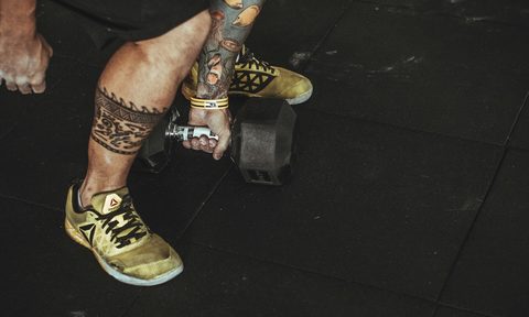 man picking up dumbbells, shot of tattooed legs
