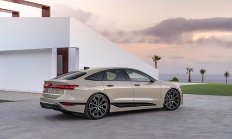 2025 Audi e-tron Sportback right side view parked beside a house with a lawn and ocean in the background.