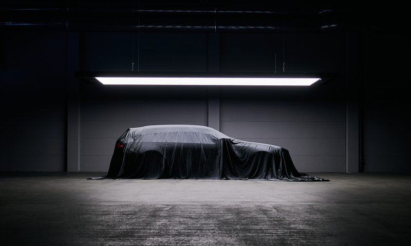 2025 BMW M5 Touring under a draped cloth with lights overhead.