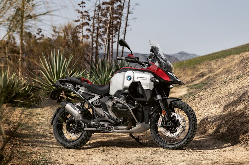2025 BMW R 1300 GS Adventure parked on a dirt road with mountains in the background.