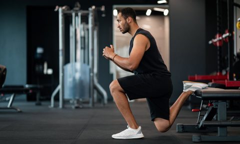 Man in gym with shorts doing Bulgarian split squat exercise in gym