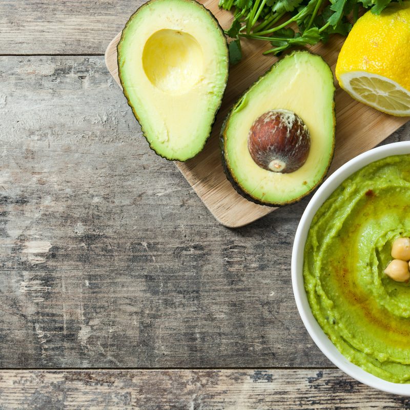 Avocado hummus avocado sliced on wooden cutting board on table