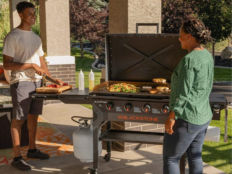 A family prepares a meal together around the Blackstone 36-inch Propane Griddle.