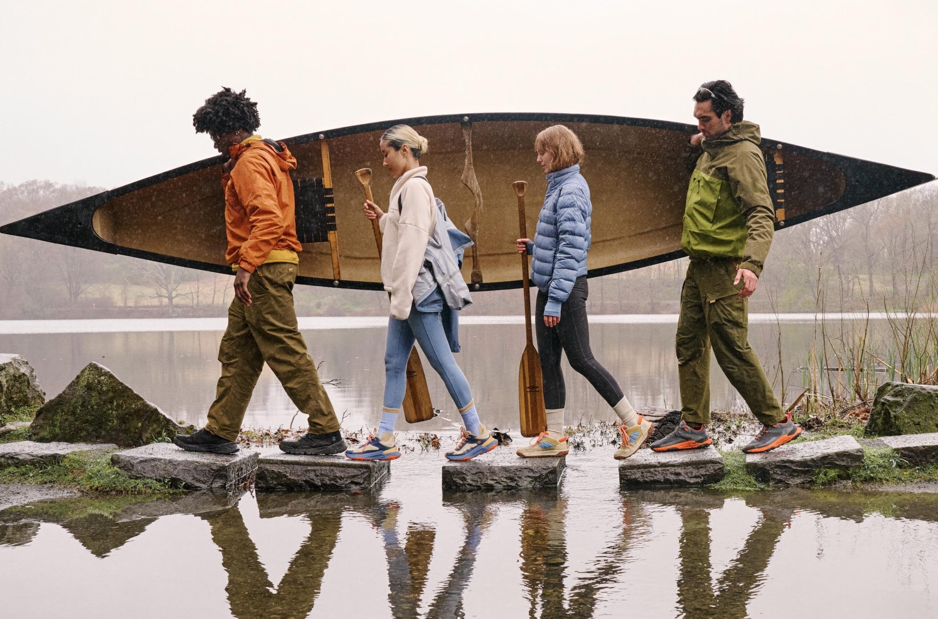 Four people carrying a kayak in hiking boots