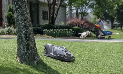 Husqvarna Automower 430XH mowing while someone does yardwork in the background