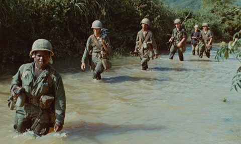 Soldiers marching through a marsh in Vietnam.