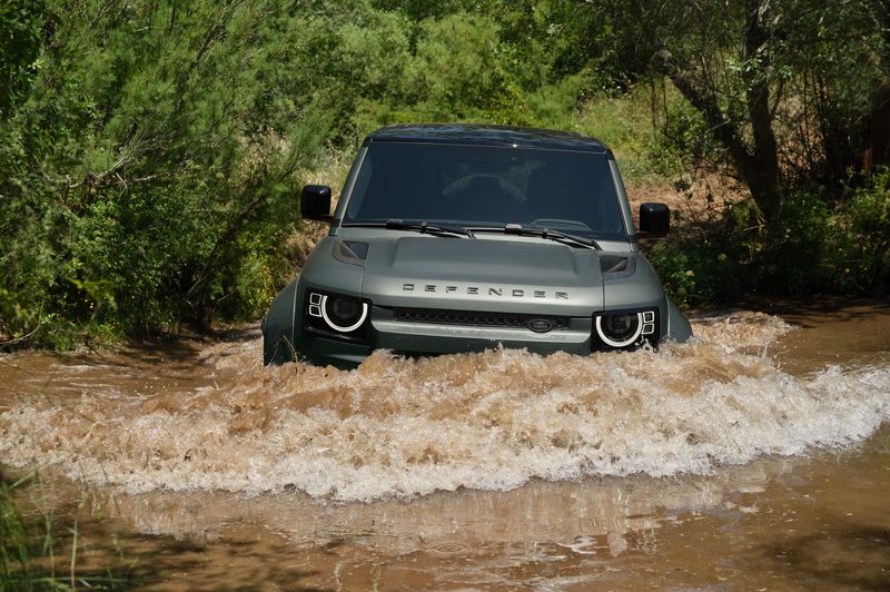 Land Rover Defender OCTA driving in a stream with water up to the headlights.