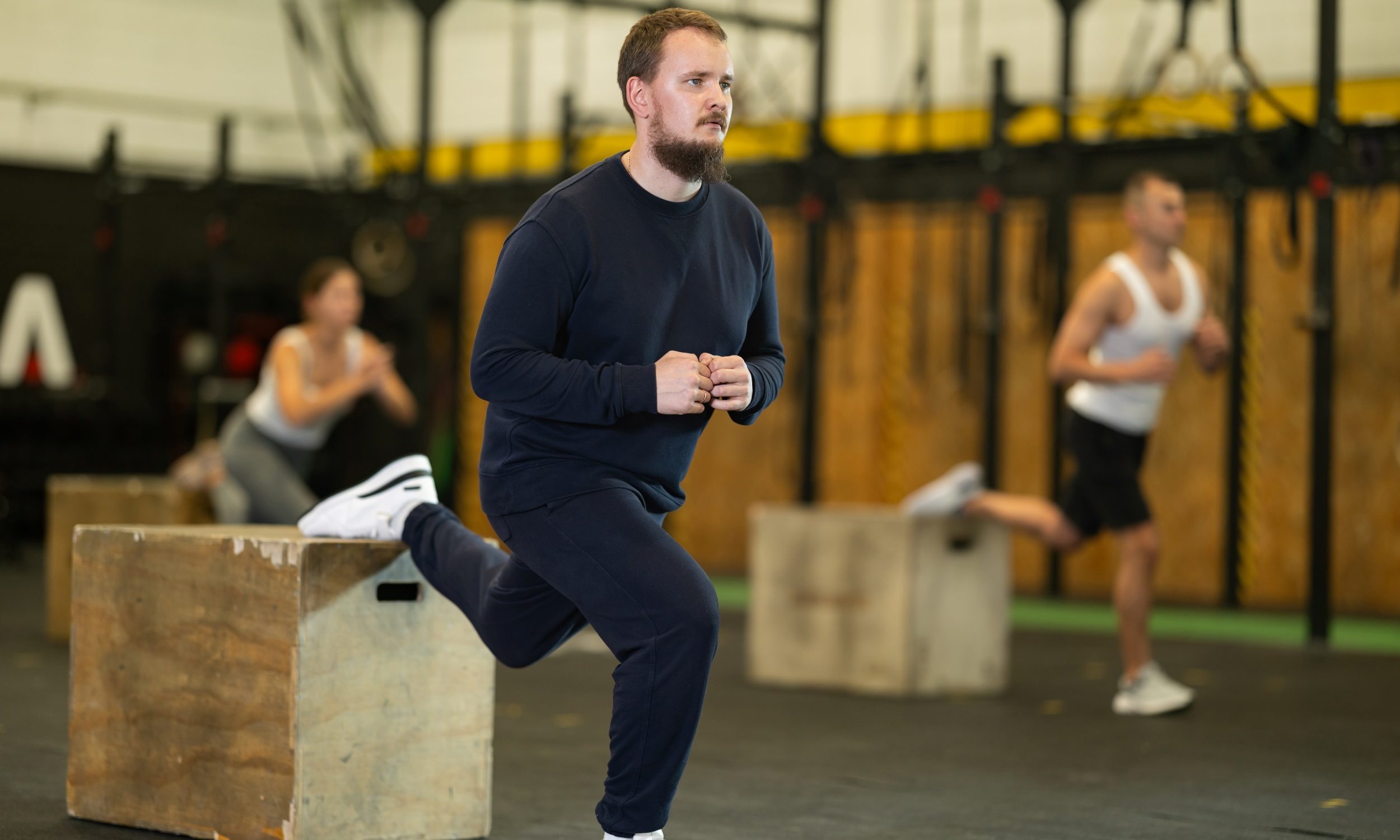 Man in gym doing bulgarian split squat exercise on a wooden box