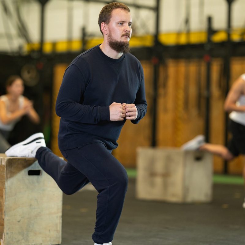Man in gym doing bulgarian split squat exercise on a wooden box