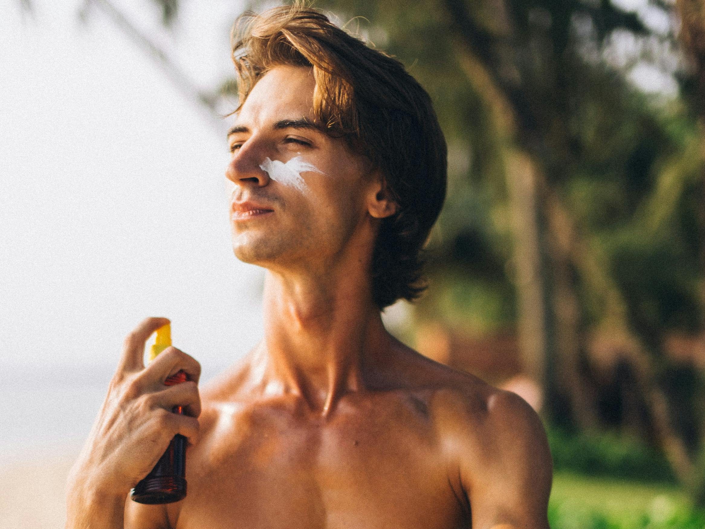 Man spraying on sunscreen outdoors