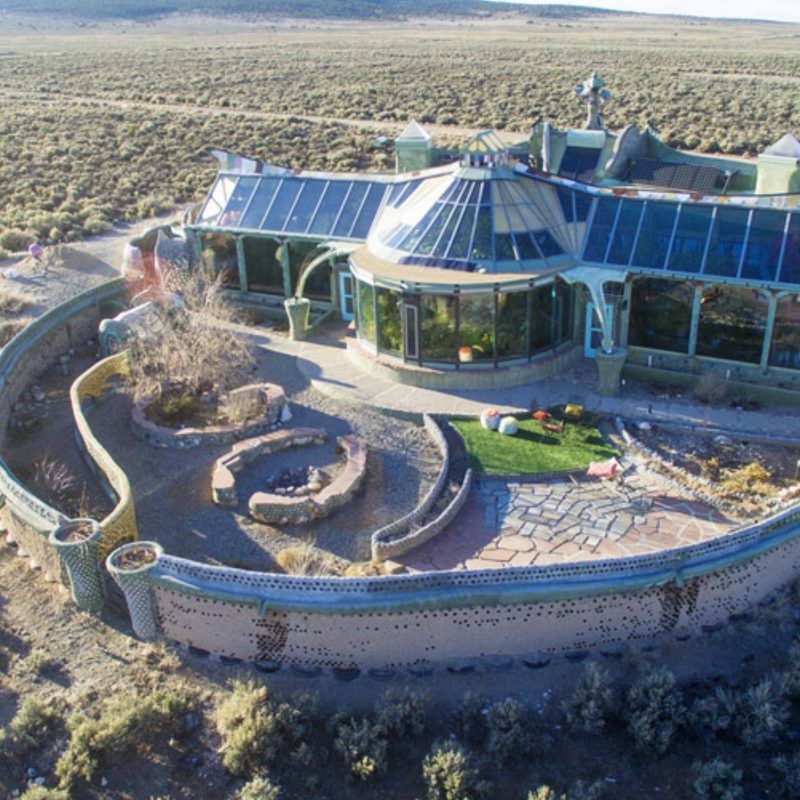 A big serpentine Earthship house with a large outdoor area
