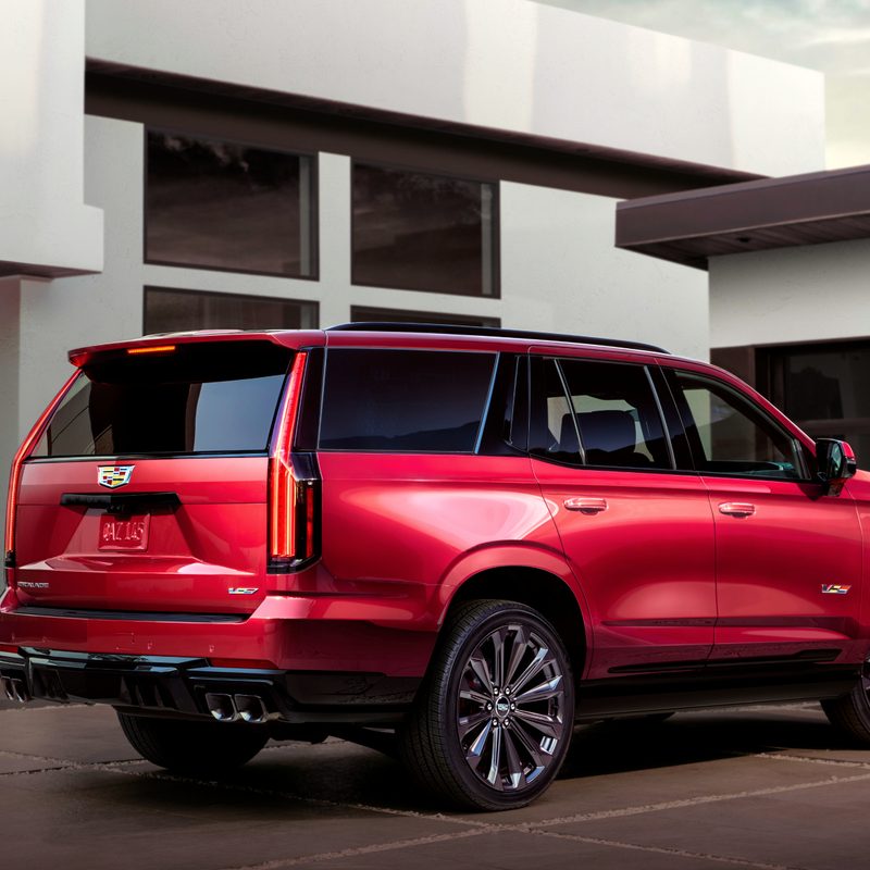Red 2025 Cadillac Escalade-v ESV parked in front of a house.